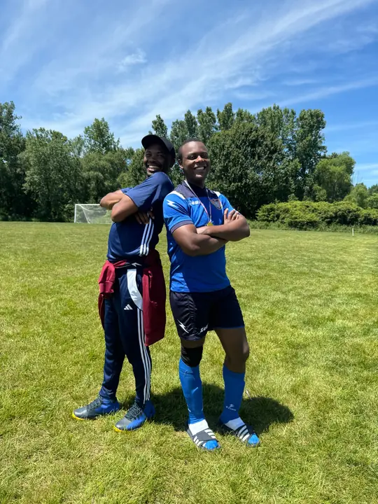 Two smiling CAVFC players posing back to back on the pitch