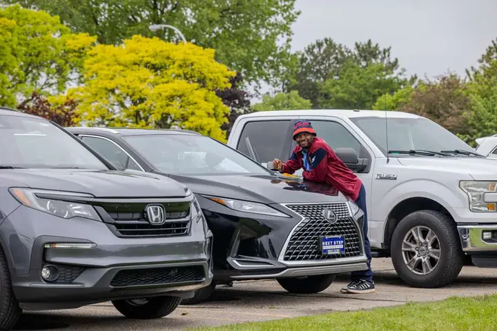Member in a maroon club jacket smiling in the parking lot
