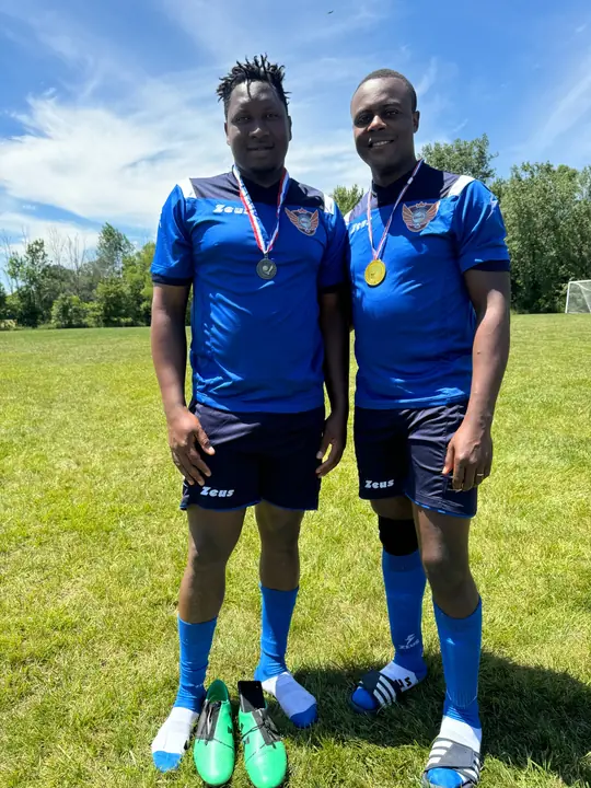 Two CAVFC players in blue kits wearing tournament medals