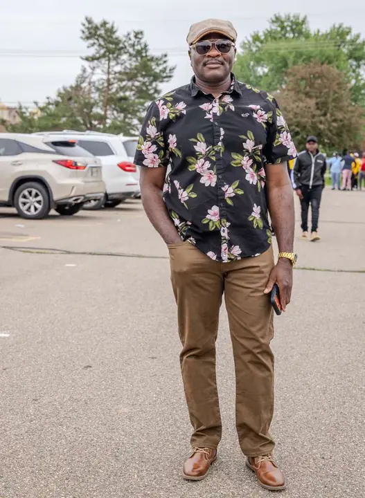 Member in a floral shirt and flat cap